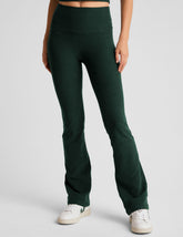 model wearing green high-waisted bootcut pants on a light gray background.